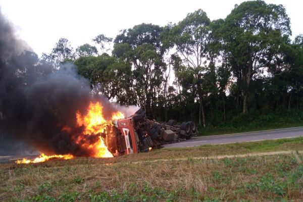 Imagem referente a notícia: Caminhão pega fogo após tombar na BR-476