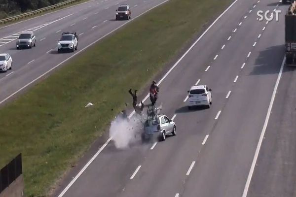 Motociclista é arremessado pra fora da rodovia após bater em carro: Veja o vídeo