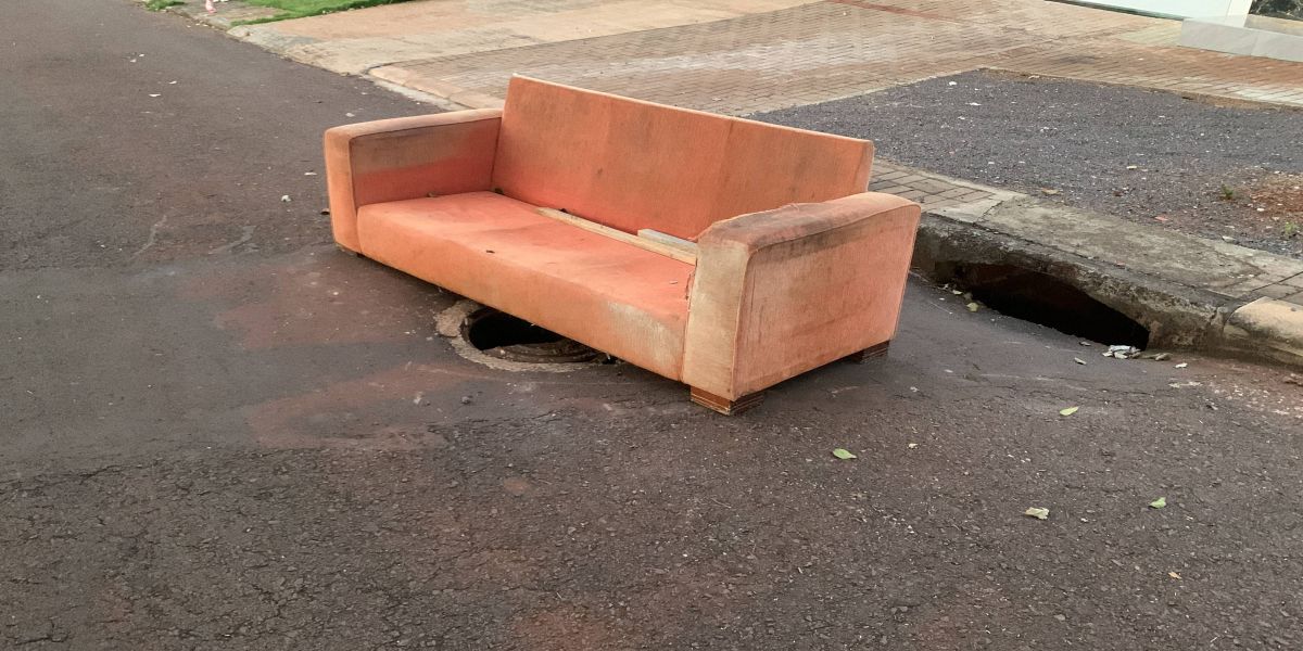 Moradores utilizam sofá para sinalizar “tampa de boca de lobo” quebrada no Bairro Periolo