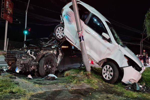 Após colisão, carro fica escorado em semáforo em cima de outro veículo