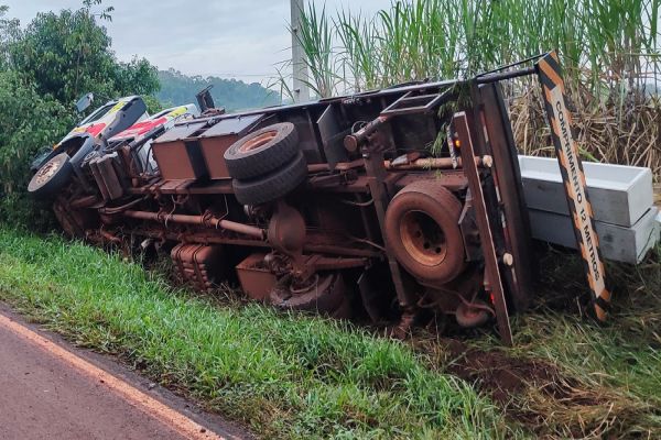 Imagem referente a notícia: Caminhão carregado de postes tomba em rodovia e deixa homem ferido em Cascavel